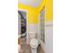 A brightly colored bathroom featuring a yellow wall, white-tiled accents and a traditional-style toilet at 1631 S Post Rd, Indianapolis, IN 46239
