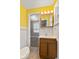 Bathroom with yellow walls, a vanity, a mirror with lighting, and white-tiled accents at 1631 S Post Rd, Indianapolis, IN 46239