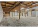 Spacious unfinished garage featuring gravel floor and open beam ceiling at 1631 S Post Rd, Indianapolis, IN 46239