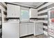 Updated laundry room with washer, dryer, cabinets, and modern gray accent wall at 1631 S Post Rd, Indianapolis, IN 46239