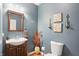 Charming powder room with wood vanity, decorative sconces and blue paint at 18112 Kinder Oak Dr, Noblesville, IN 46062