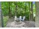 Secluded fire pit area with three Adirondack chairs nestled amongst mature trees and a bed of gravel at 18112 Kinder Oak Dr, Noblesville, IN 46062