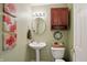 Stylish powder room with a pedestal sink, decorative mirror, and charming wall art at 18112 Kinder Oak Dr, Noblesville, IN 46062