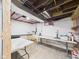 Unfinished basement with concrete floors, exposed ceiling, tables, and storage areas at 1910 W 10Th St, Anderson, IN 46016