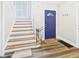 Inviting foyer with wood-look floors, painted staircase, and blue front door at 1910 W 10Th St, Anderson, IN 46016