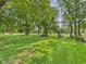 Expansive green back yard with mature shade trees and white fencing in the distance at 2126 Tartan Rd, Anderson, IN 46012