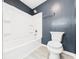 Clean bathroom featuring a tub with shower and a toilet with a matching blue wall at 2126 Tartan Rd, Anderson, IN 46012