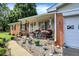 Cozy front porch with decorative accents, potted plants, and seating, leading to a charming brick home at 2608 E 500 N, Whiteland, IN 46184