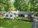 Exterior shot of a white ranch-style home with black shutters, landscaped front yard, and brick walkway at 3312 W 42Nd St, Indianapolis, IN 46228