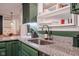A well-lit kitchen showcases green cabinetry, granite countertops, and a stainless steel sink with stylish faucet at 3312 W 42Nd St, Indianapolis, IN 46228