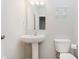 Clean bathroom featuring a pedestal sink, toilet, mirror, and glass shelves at 3643 Thomas Jefferson St, Westfield, IN 46074