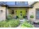 Inviting front porch with a vibrant green door, brick accents, and lush landscaping at 3715 Pitkin Rd, Martinsville, IN 46151