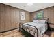 Rustic bedroom featuring wood paneled walls, iron bed frame, and a bright overhead light fixture at 4418 North Dr, Quincy, IN 47456