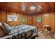 Cozy bedroom with wood paneled walls, featuring an iron bed frame and natural light from the windows at 4418 North Dr, Quincy, IN 47456