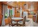 Dining area with wooden walls, a round table set, a window view, and kitchen access at 4418 North Dr, Quincy, IN 47456