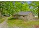 Stone cottage with mature trees, a gravel driveway, and a well-maintained landscape at 4418 North Dr, Quincy, IN 47456