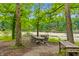 Outdoor dining area with a large table and chairs by the lake surrounded by trees and lush greenery at 4418 North Dr, Quincy, IN 47456