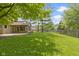 This well-maintained backyard showcases an expansive lawn, mature trees, a screened porch, and a patio area at 5037 Surrey Ln, Carmel, IN 46033