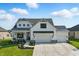 Striking two-story residence with white siding, black trim, a cozy front porch, and an attached three-car garage at 5668 Champion Way, Greenwood, IN 46143