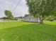 Side yard view of home with lush green lawn and mature tree providing ample shade at 624 10Th St, Chesterfield, IN 46017