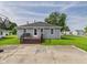 Exterior view of a charming home with a deck, gray siding, a well-maintained lawn, and a concrete parking area at 624 10Th St, Chesterfield, IN 46017