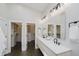 Bright bathroom featuring a double vanity with black faucets and large mirrors with walk in closets on each side at 704 Parkway Ave, Indianapolis, IN 46203