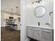 Stylish powder room with a modern vanity, round mirror, and view into the adjacent kitchen at 704 Parkway Ave, Indianapolis, IN 46203