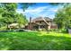 Backyard featuring a covered patio, fire pit, lush lawn, and a brick home at 7648 W Williamswood Dr, New Palestine, IN 46163