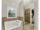 Bathroom featuring a soaking tub, glass-enclosed shower, and natural light at 7648 W Williamswood Dr, New Palestine, IN 46163