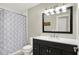 Well-lit bathroom with modern vanity, mirror, and shower-tub combo featuring a stylish patterned curtain at 7648 W Williamswood Dr, New Palestine, IN 46163