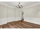 Bright dining area featuring wainscoting, modern chandelier, and hardwood flooring, perfect for entertaining at 7648 W Williamswood Dr, New Palestine, IN 46163