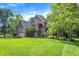 Landscaped front yard with mature trees surrounding a brick home with a three-car garage and well-manicured lawn at 7648 W Williamswood Dr, New Palestine, IN 46163
