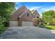 Beautiful brick home with a three-car garage, manicured lawn, and mature trees providing shade and privacy at 7648 W Williamswood Dr, New Palestine, IN 46163