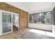 Bright sun room with brick accent wall, tile floor, and sliding doors leading to an outdoor patio at 7648 W Williamswood Dr, New Palestine, IN 46163