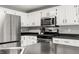 Bright kitchen featuring white cabinets, stainless steel appliances, and dark countertops at 7833 Meadow Bend Dr, Indianapolis, IN 46259