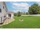 Expansive backyard with a patio set, brick firepit, lush lawn, and white fencing at 985 Farmington Trl, Brownsburg, IN 46112