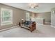 Carpeted living room features a wooden futon, multiple windows, and a view of the staircase at 985 Farmington Trl, Brownsburg, IN 46112