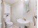 Powder room with pedestal sink, toilet, cabinet, and neutral wallpaper at 12043 Searay Dr, Indianapolis, IN 46236