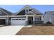 New construction exterior showcasing a two-car garage, gray siding, stone accents, and a well-manicured lawn under a clear blue sky at 12516 Morning Ridge Way, Noblesville, IN 46060