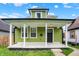 Eye-catching green home with a modern black door and a charming covered front porch at 1338 N Parker Ave, Indianapolis, IN 46201