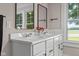 Bathroom featuring double sinks with white countertop, black hardware, and nature views at 14855 E State Road 46, Columbus, IN 47203