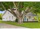Charming home with a large tree in the front yard and a welcoming front porch with seating area at 14855 E State Road 46, Columbus, IN 47203