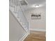 Bright hallway with wood floors, white trim, staircase, and modern art at 14855 E State Road 46, Columbus, IN 47203