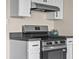 Close-up of modern range with stainless steel range hood and gray countertop at 14855 E State Road 46, Columbus, IN 47203