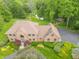 Charming aerial view of a brick home showcasing the beautiful landscaping, mature trees, and a nearby stream at 1497 N 200 W, Greenfield, IN 46140