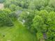 Aerial view showcasing lush greenery, a tranquil stream, and a manicured lawn, highlighting the property's natural beauty at 1497 N 200 W, Greenfield, IN 46140