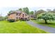 Two-story brick home featuring a curved driveway and beautifully landscaped front yard under a cloudy sky at 1497 N 200 W, Greenfield, IN 46140