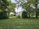 A grassy backyard is surrounded by mature trees and greenery, creating a private outdoor space at 1510 Chester St, Anderson, IN 46012
