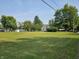 A house situated on an expansive green lawn with mature trees creates a picturesque scene at 1510 Chester St, Anderson, IN 46012