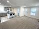 Open-concept living space with neutral carpet flowing into the kitchen with a dark island and seating at 1628 Spann Ave, Indianapolis, IN 46203